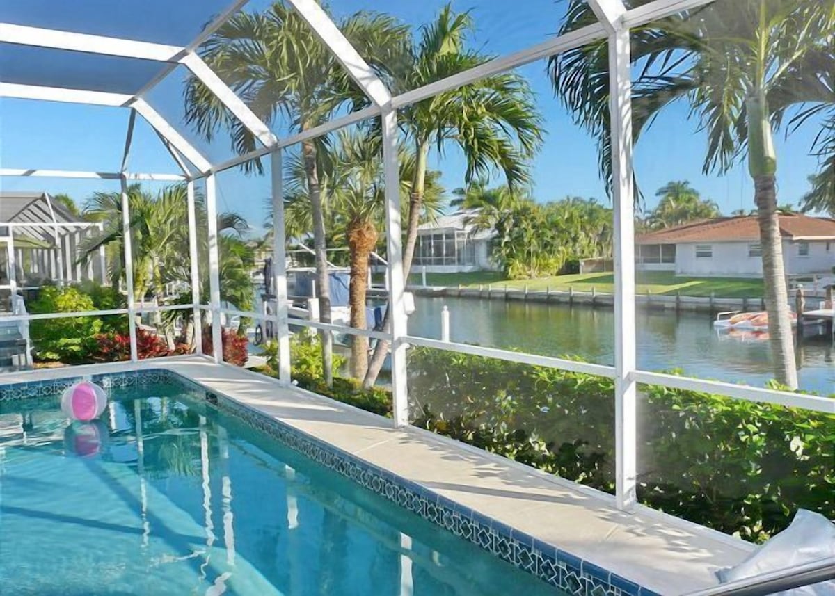 Screened lanai pool looking out to a canal and palms