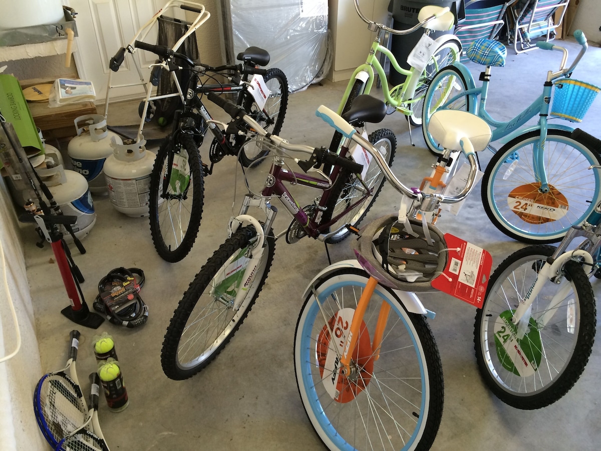 A garage with multiple bicycles, gas cylinders, and a tennis racket.