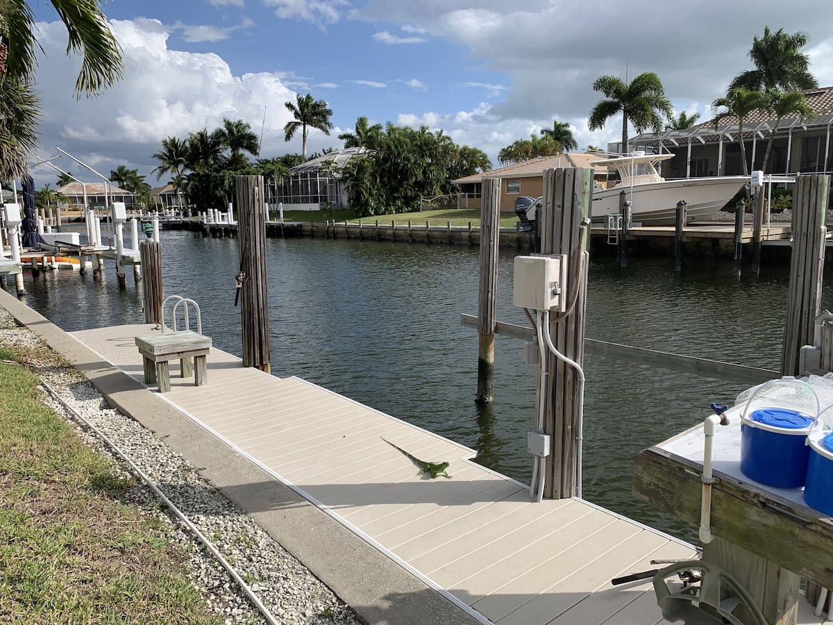 A marina with docks, boats, and a grassy area with palm trees.