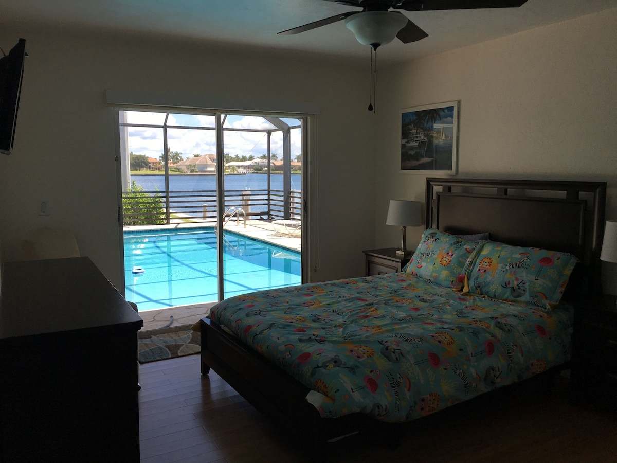 Bedroom with a view through sliding doors to the pool and water