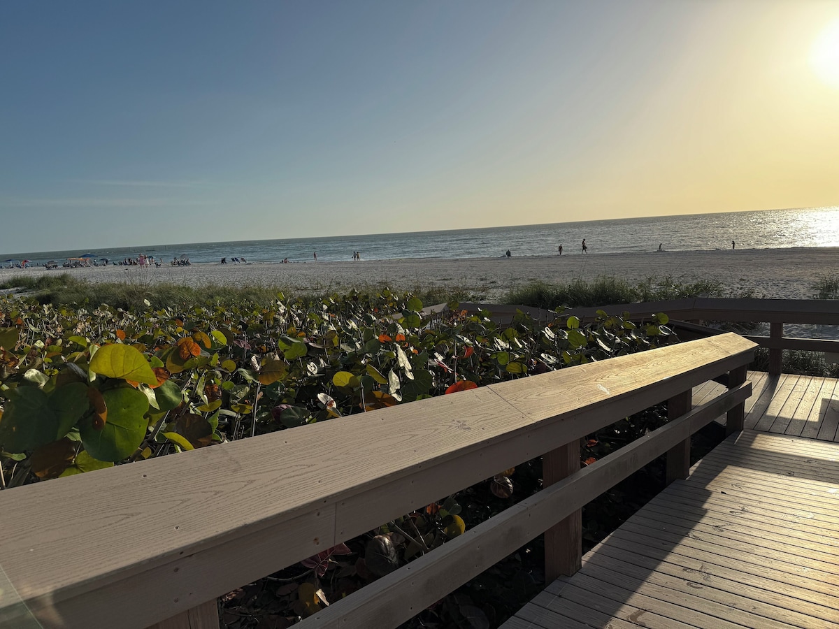 A wooden deck with a view of the beach and ocean.