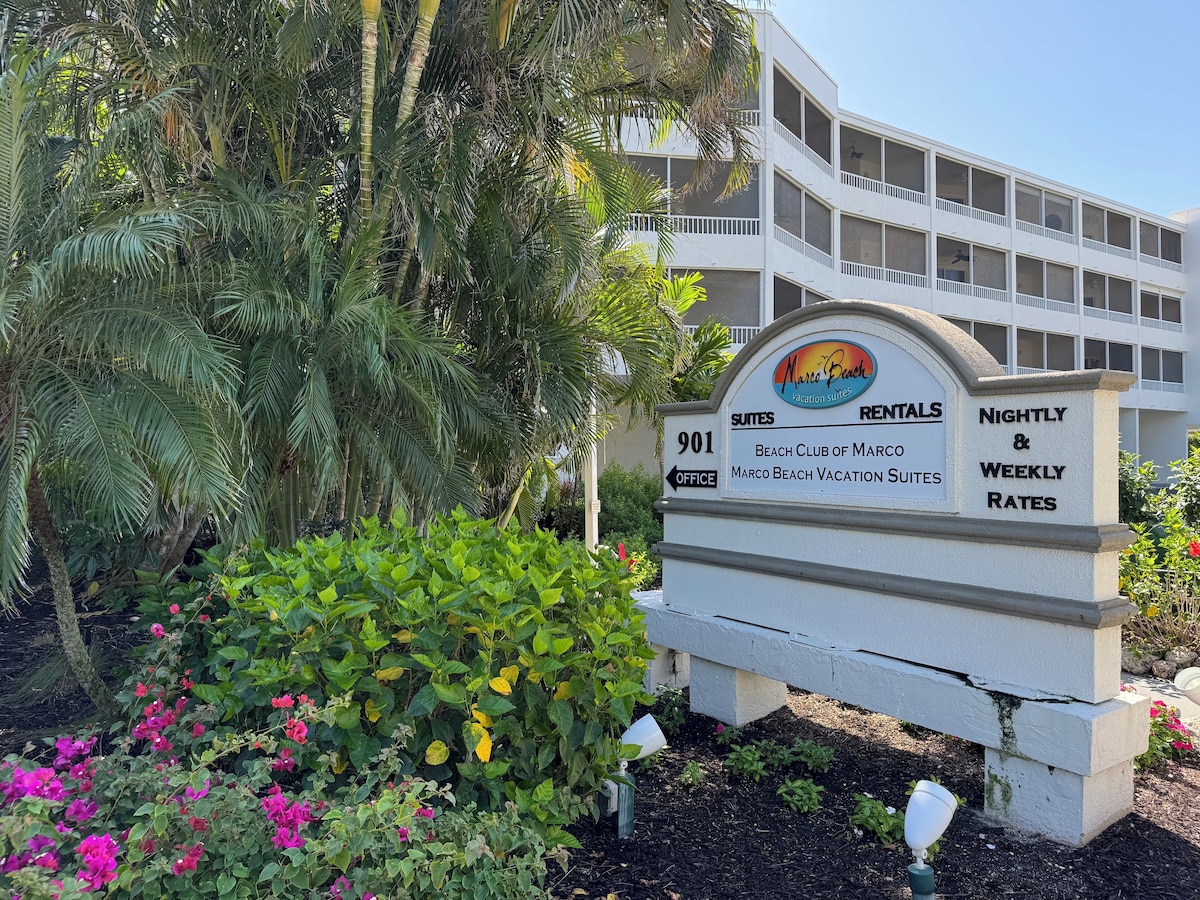 A sign for Marco Beach Vacation Suites with a direction to the office.