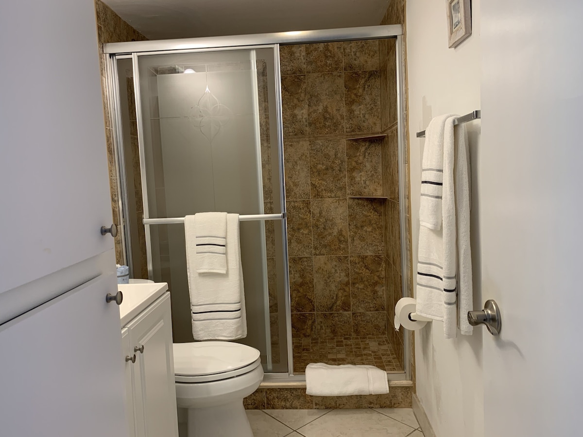 A bathroom with a toilet, a shower with a glass door, and a towel rack.