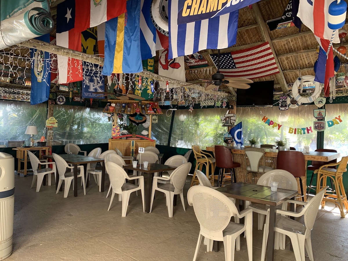 A restaurant with multiple tables and chairs, various flags, and a Happy Birthday banner.