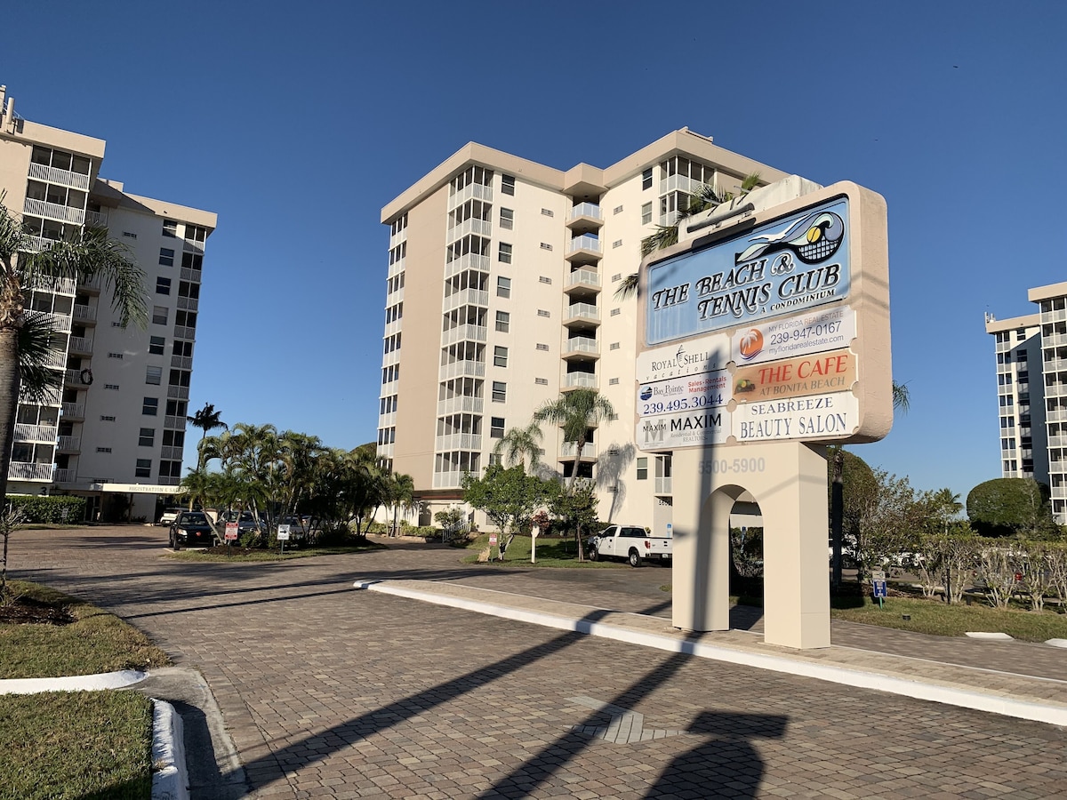 A multi-story building with balconies, a sign for The Beach Club Tennis Club, and a Royal Shell Vacations sign.