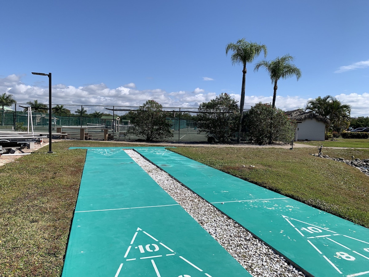 A shuffleboard court with numbered areas and a surrounding fence.