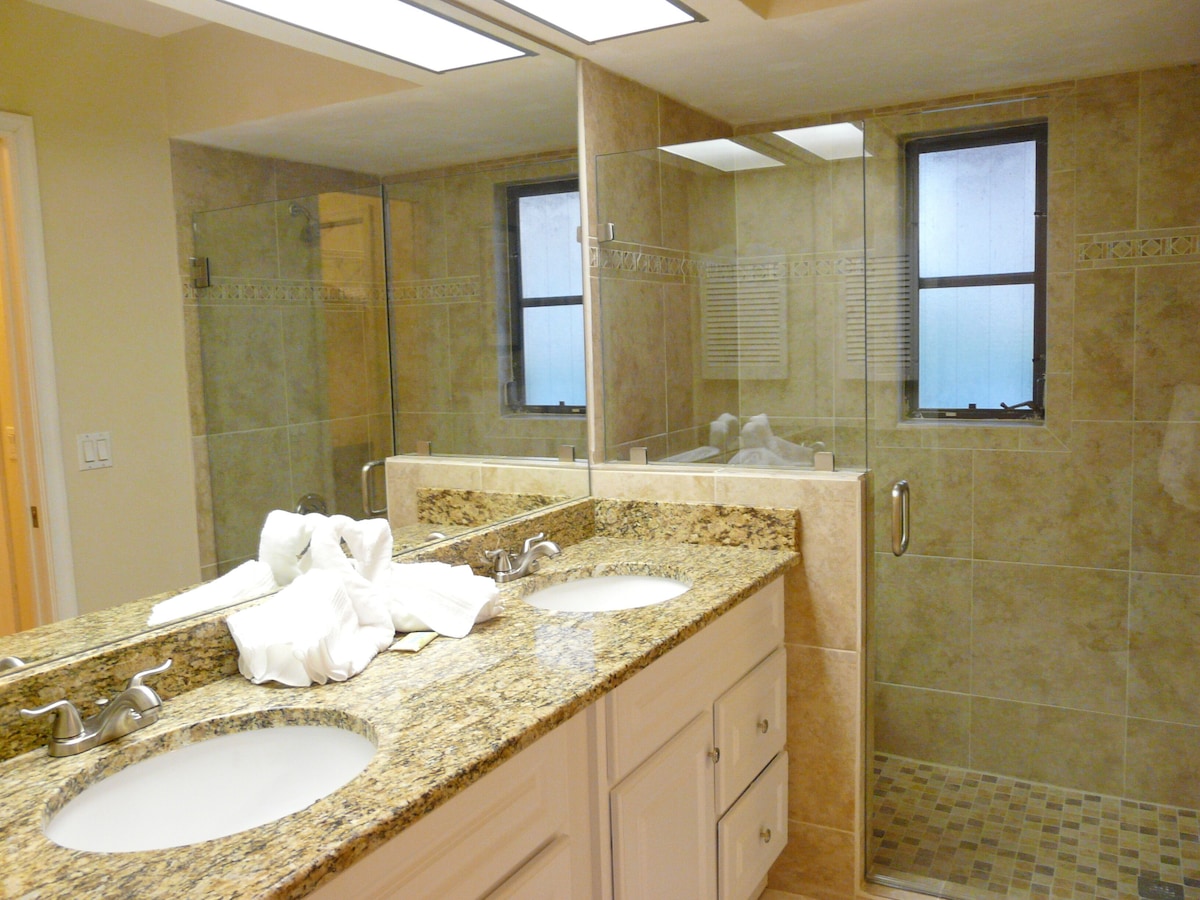 A bathroom with two sinks, a large mirror, and a shower area.
