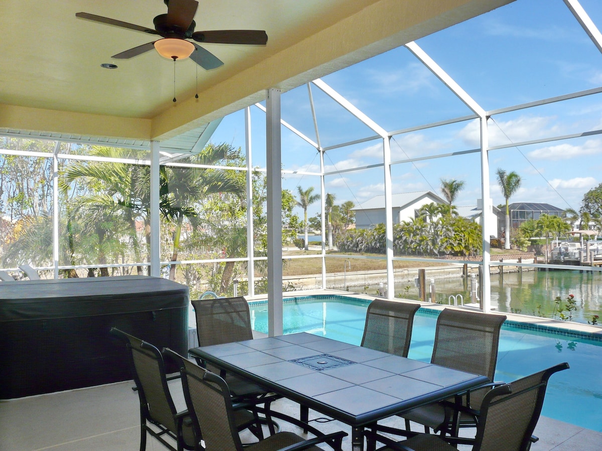A covered outdoor area with a pool, seating, and a ceiling fan.