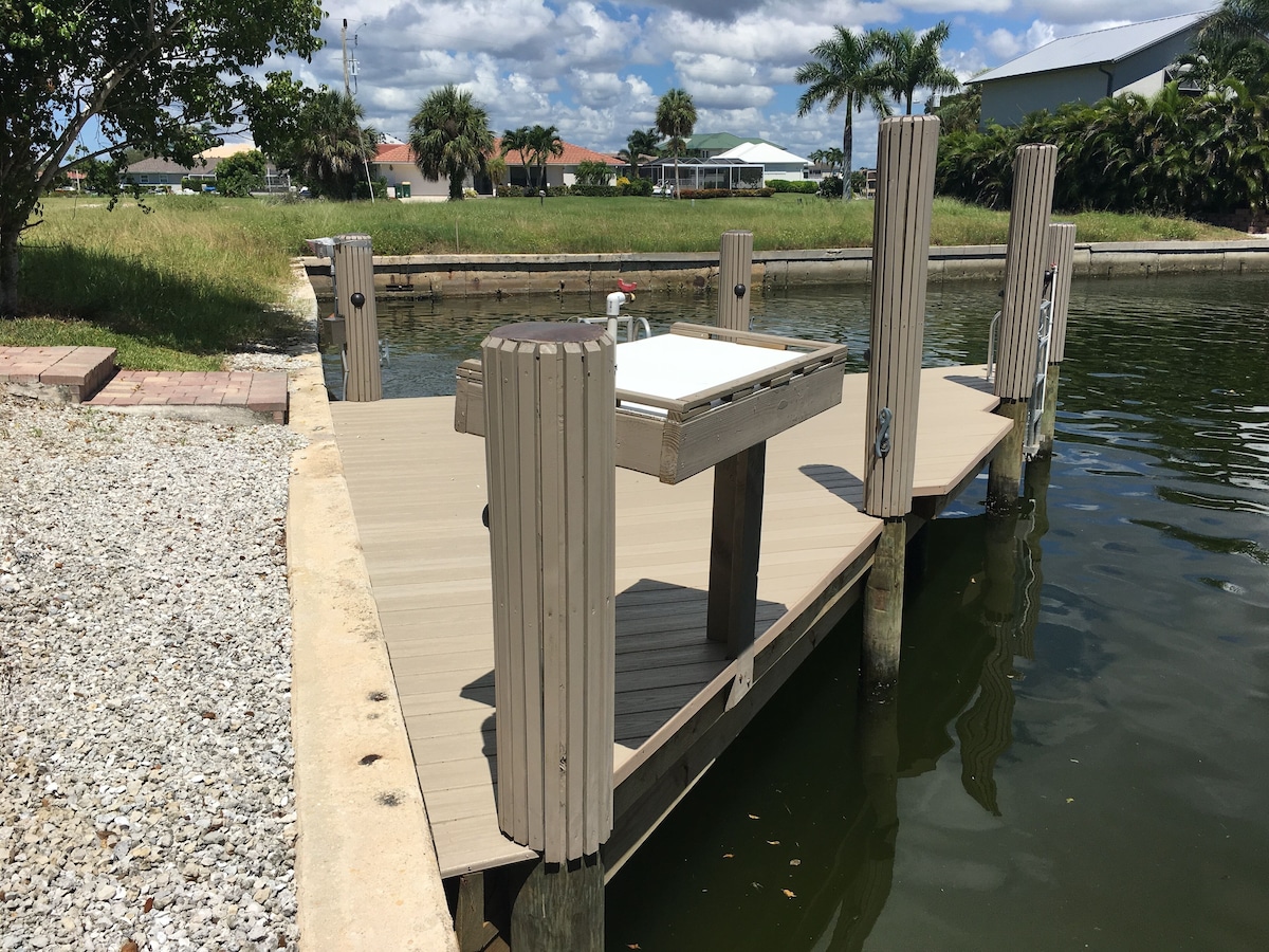 A wooden dock extending into a calm body of water, with a small table and bench at the end.