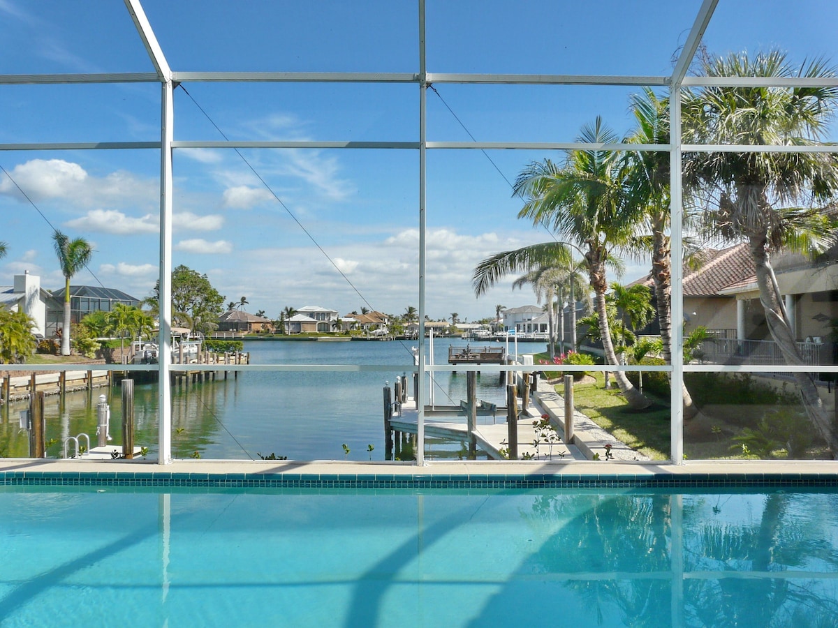 A pool with a view of a marina and houses in the background.