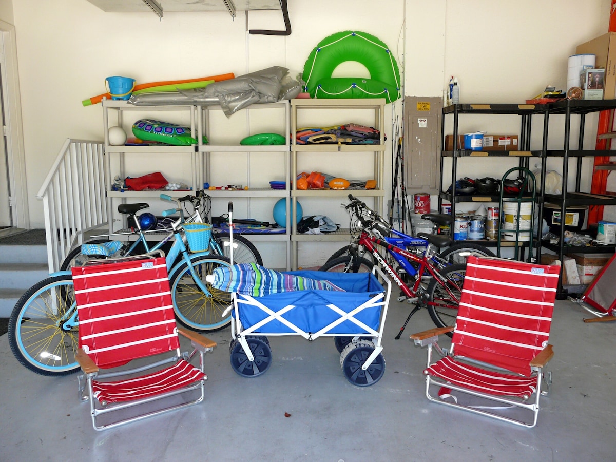 A garage with bicycles, a beach chair, and storage shelves.