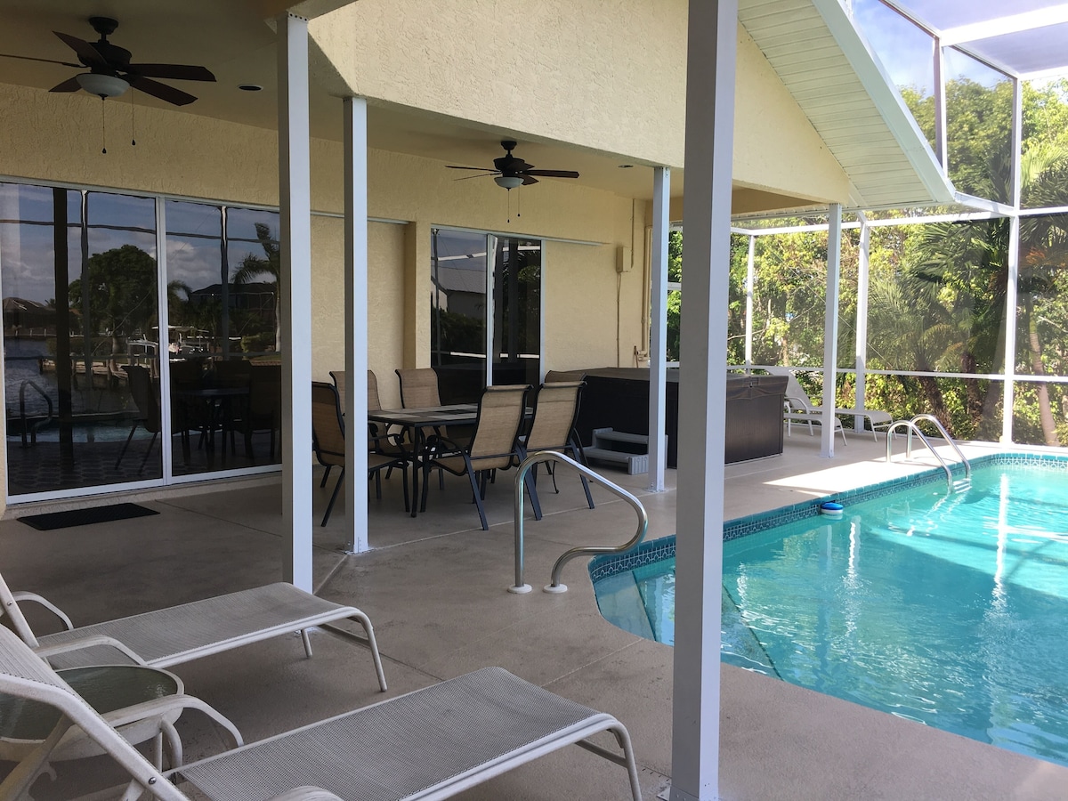 An outdoor pool area with lounge chairs, a table, and a ceiling fan.