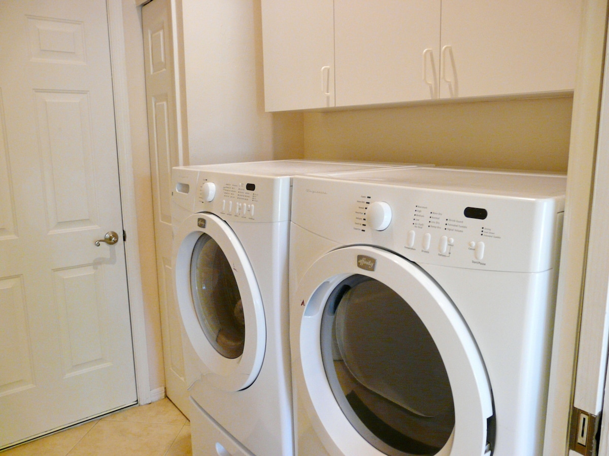 A laundry room with two front-loading washing machines and a white door.