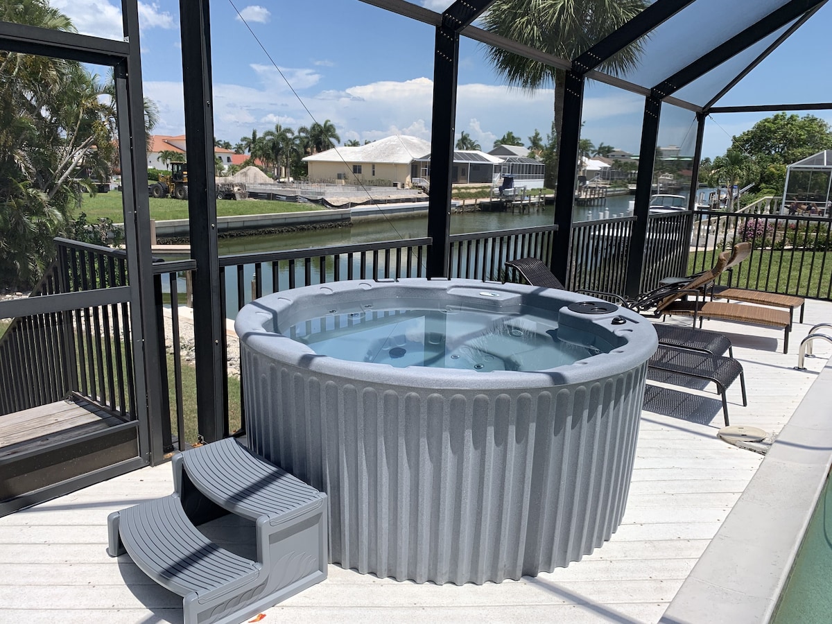 A hot tub with a glass enclosure, surrounded by a deck with outdoor furniture.