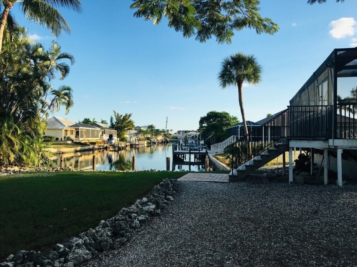 A waterfront property with a dock, a covered walkway, and a grassy area.