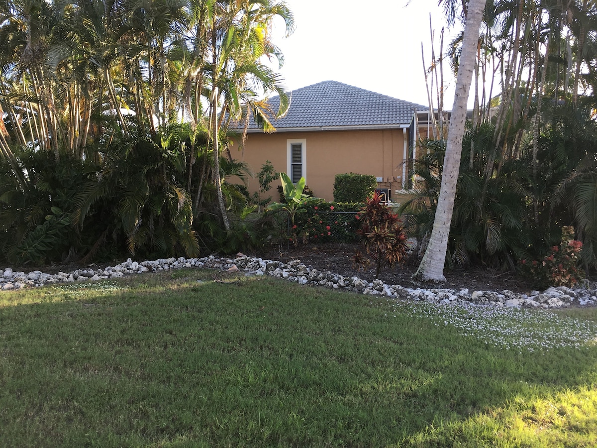 A house with a tiled roof, surrounded by a well-maintained garden with various plants and a grassy lawn.
