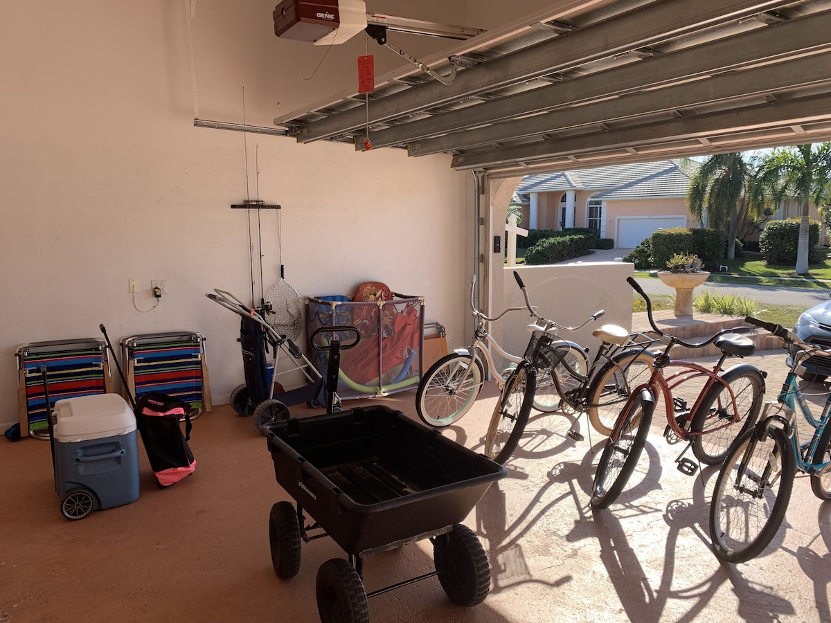 A garage with bicycles, a wheelbarrow, and a colorful cart.