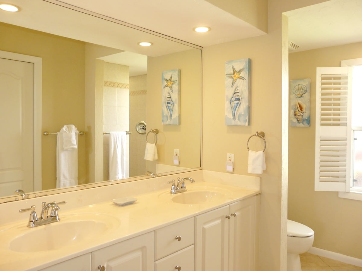A bathroom with two sinks, a large mirror, and artwork on the walls.